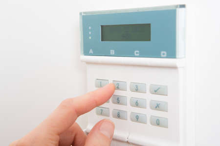 Woman Setting Control Panel On Home Security System