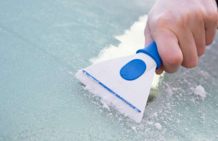 Close Up Of Hand Scraping Ice From Car Windshield With Scraper