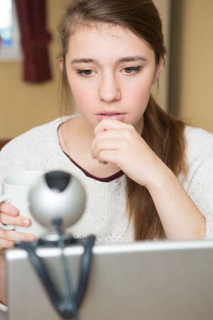 Worried Teenage Girl Using Webcam On Computer