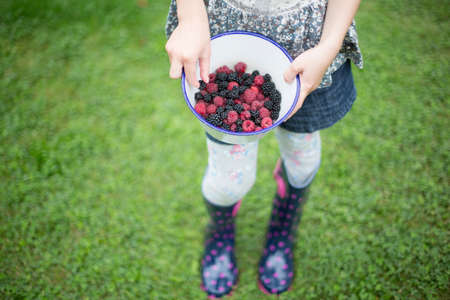 Close Up Of Girl Holding Bowl Of Raspberries And Blackberriesの写真素材