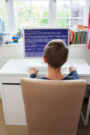 Teenage Boy In Bedroom Writing Computer Codeの写真素材
