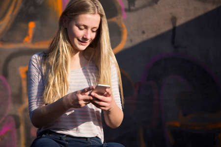 Teenage Girl Texting On Mobile Phone In Playgroundの写真素材
