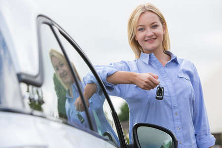 Young Female Driver Holding Car Keys Next To Vehicleの写真素材