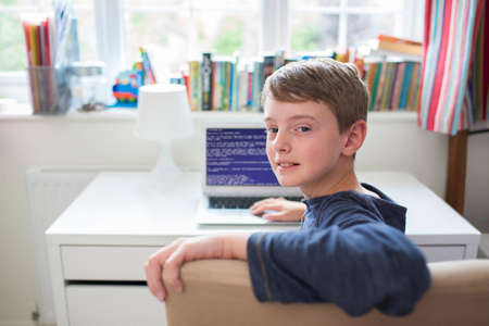 Teenage Boy In Bedroom Writing Computer Codeの写真素材