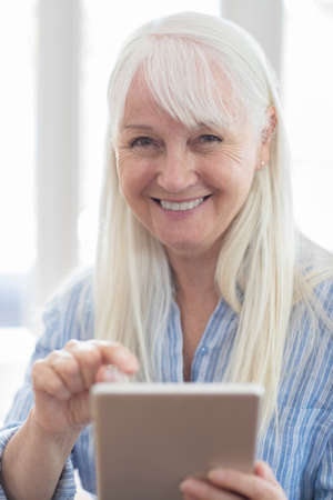 Portrait Of Senior Woman Using Digital Tablet At Homeの写真素材