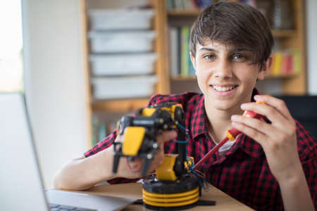 Portrait Of Teenage Boy Building Robotic Arm At Schoolの写真素材