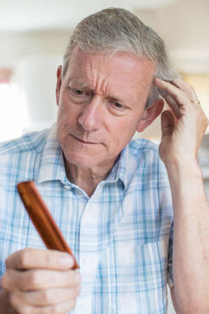 Senior Man With Comb Concerned About Hair Loss