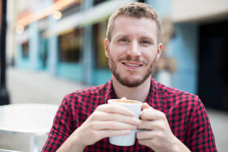 Portrait Of Young Man Drink Coffee At Outdoor Cafe Tableの写真素材