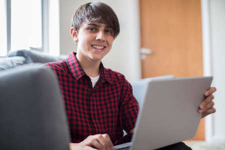 Portrait Of Teenage Boy Working On Laptop At Homeの写真素材