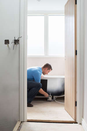 Plumber Installing New Bath Into Bathroomの写真素材