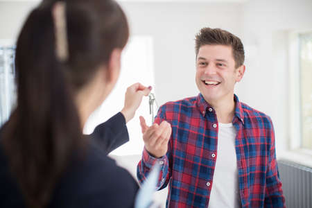 Man Collecting Keys To New Home From Female Realtorの写真素材