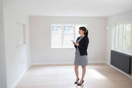 Female Estate Agent With Digital Tablet Looking Around Vacant Property For Valuationの写真素材