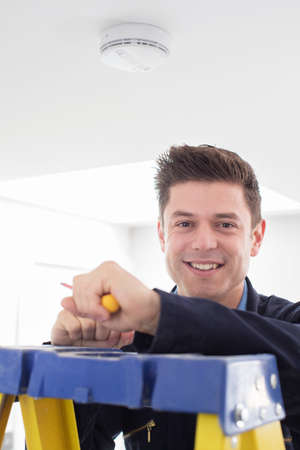 Man Installing Smoke Or Carbon Monoxide Detectorの写真素材