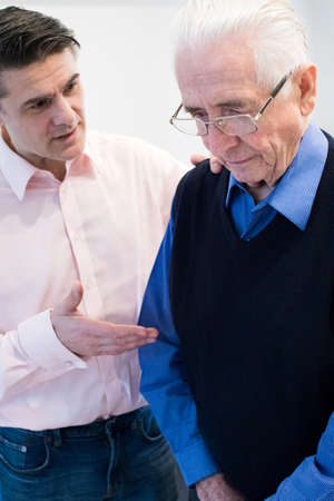 Confused Senior Man With Adult Son At Homeの写真素材