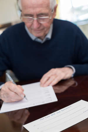 Senior Man Signing Last Will And Testament At Homeの写真素材