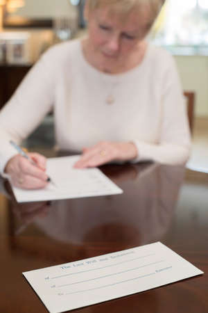 Senior Woman Signing Last Will And Testament At Home