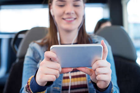 Young Woman Watching Movie On Mobile Phone During Journey To Work
