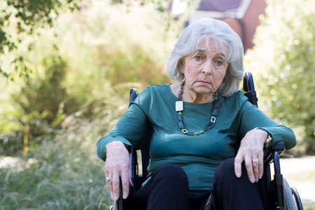 Depressed Senior Woman In Wheelchair Sitting Outdoorsの写真素材