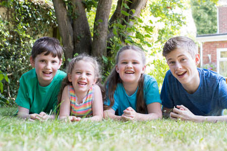 Portrait Of Four Brothers And Sisters Lying In Garden At Homeの写真素材
