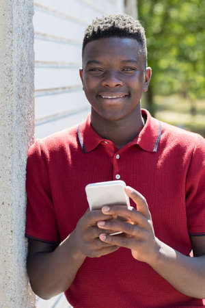 Portrait Of Teenage Boy Outdoors Sending Text Message From Mobile Phone