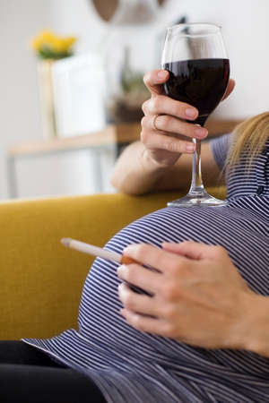 Close Up Of Pregnant Woman Smoking Cigarette And Drinking Wineの写真素材
