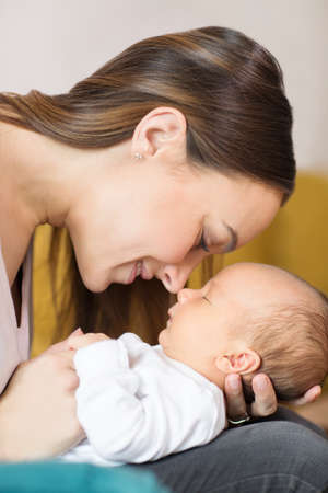 Loving Mother Cuddling Baby Son And Touching Nosesの写真素材