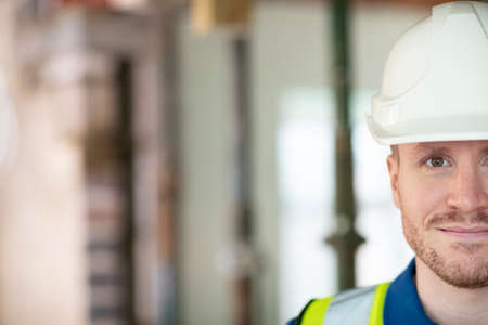 Cropped Portrait Of Male Construction Worker On Building Site Wearing Hard Hat