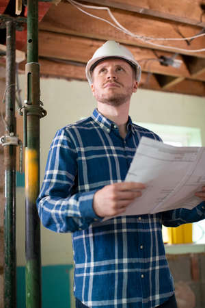 Architect Inside House Being Renovated Studying Plansの写真素材