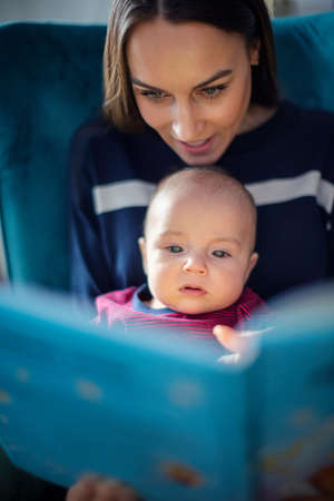 Baby Son Sitting On Mothers Lap Reading Story Book Togetherの写真素材