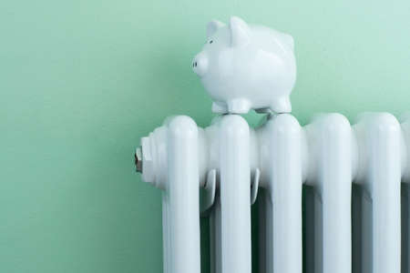 Piggy Bank Balanced On Radiator To Illustrate Energy Costsの写真素材