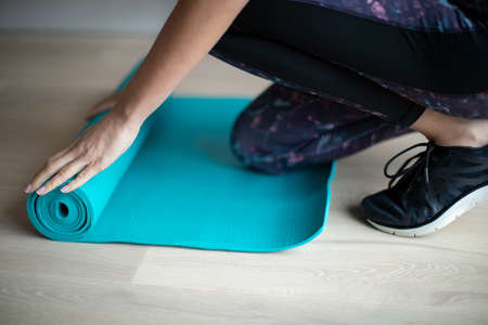 Close Up Of Woman Rolling Out Exercise Mat On Floor Before Exercise