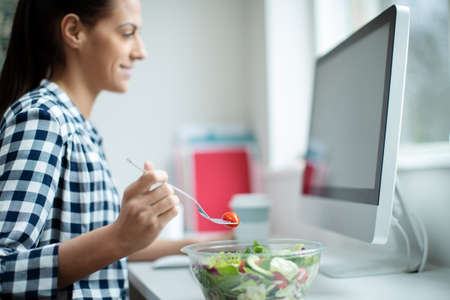 Female Worker In Office Having Healthy Salad Lunch At Deskの写真素材