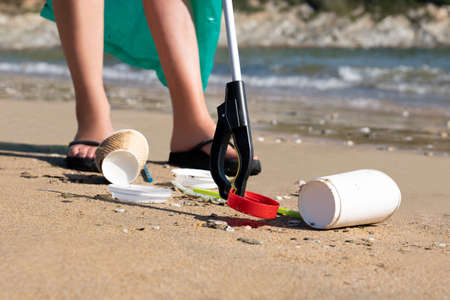 Close Up Of Person Collecting Plastic Waste From Polluted Beach Using Litter Pickerの写真素材