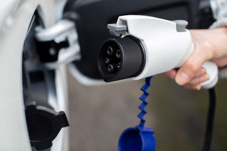 Close Up Of Hand Attaching Power Cable To Environmentally Friendly Zero Emission Electric Carの写真素材