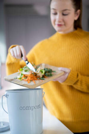 Woman Making Compost From Vegetable Leftovers In Kitchenの写真素材
