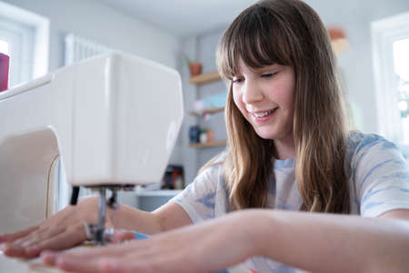 Young Girl Learning How To Use Sewing Machine At Homeの写真素材