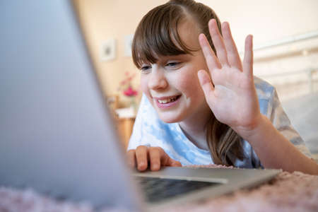 Smiling Girl In Bedroom Talking With Friends On Social Media Using Laptop Computerの写真素材