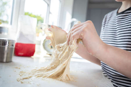 Close Up Of Portrait Of Girl With Messy Hands Having Fun In Kitchen Kneading Dough For Bakingの写真素材