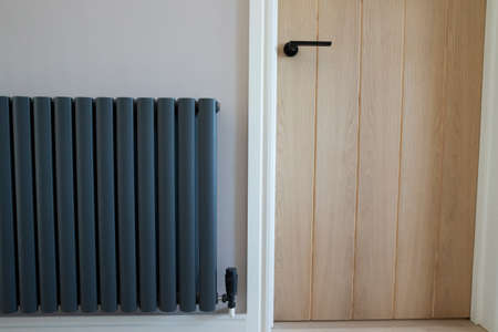Close Up Of Closed Wooden Door And Stylish Central Heating Radiator In Modern Homeの写真素材