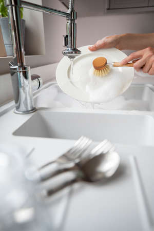 Woman Washing Up At Home Using Eco Dish Brush For Sustainable Lifestyleの写真素材