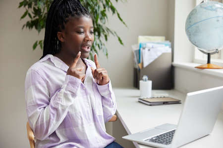 Teenage Girl Having Conversation Using Sign Language On Laptop At Home