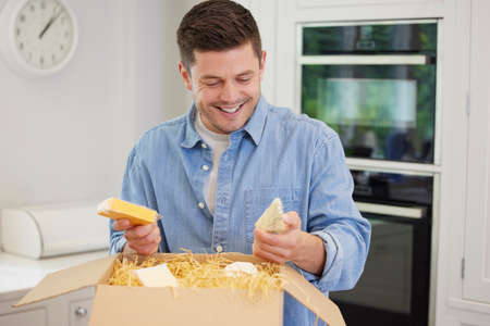 Man Unpacking Online Luxury Cheeses Delivered To Homeの写真素材