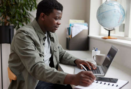 Enthusiastic Young Man Working From Home On Laptopの写真素材