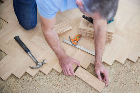 Overhead View Of Carpenter Or Builder Laying New Wood Block Parquet Parquet Floor In Kitchen At Homeの写真素材