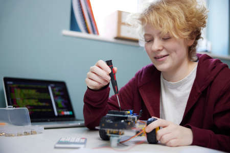 Teenage Girl With Laptop Building Robot On Desk In Bedroom At Homeの写真素材