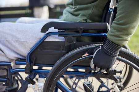 Close Up Of Teenage Boy Wearing Protective Gloves In Wheelchair In Parkの写真素材