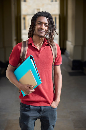 Portrait Of Male Student Carrying Files Outside University Building In Oxford UKの写真素材