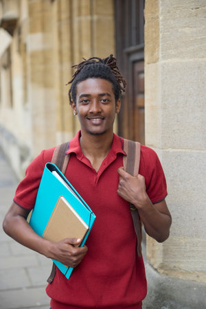 Portrait Of Male Student Carrying Files Outside University Building In Oxford UKの写真素材
