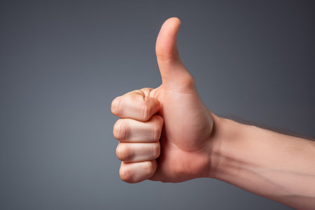 Generative AI Image Of Close Up Of Hand With Thumbs Up To Show OK Or Approval On Grey Backgroundの素材