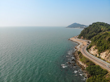 Coastal Highway Winding Along the Scenic Ocean Shore. Road cut off the sea and mountains. The blue sea along the way. Photos from the top to the bottom. Aerial photos.の写真素材